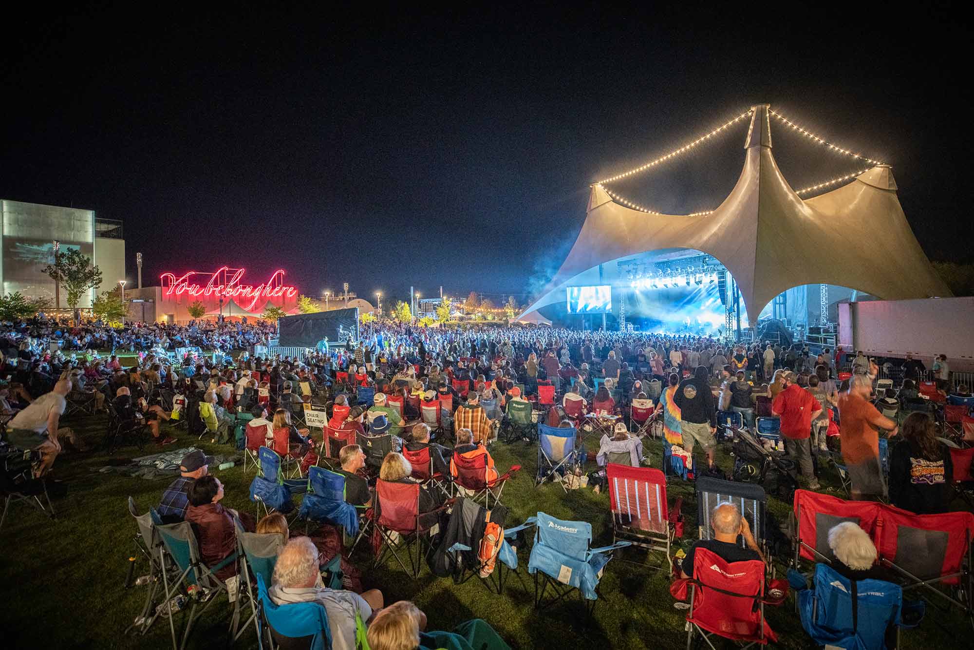 A crowd looks on to the stage on the momentary green at FreshGrass Bentonville 2021 at night