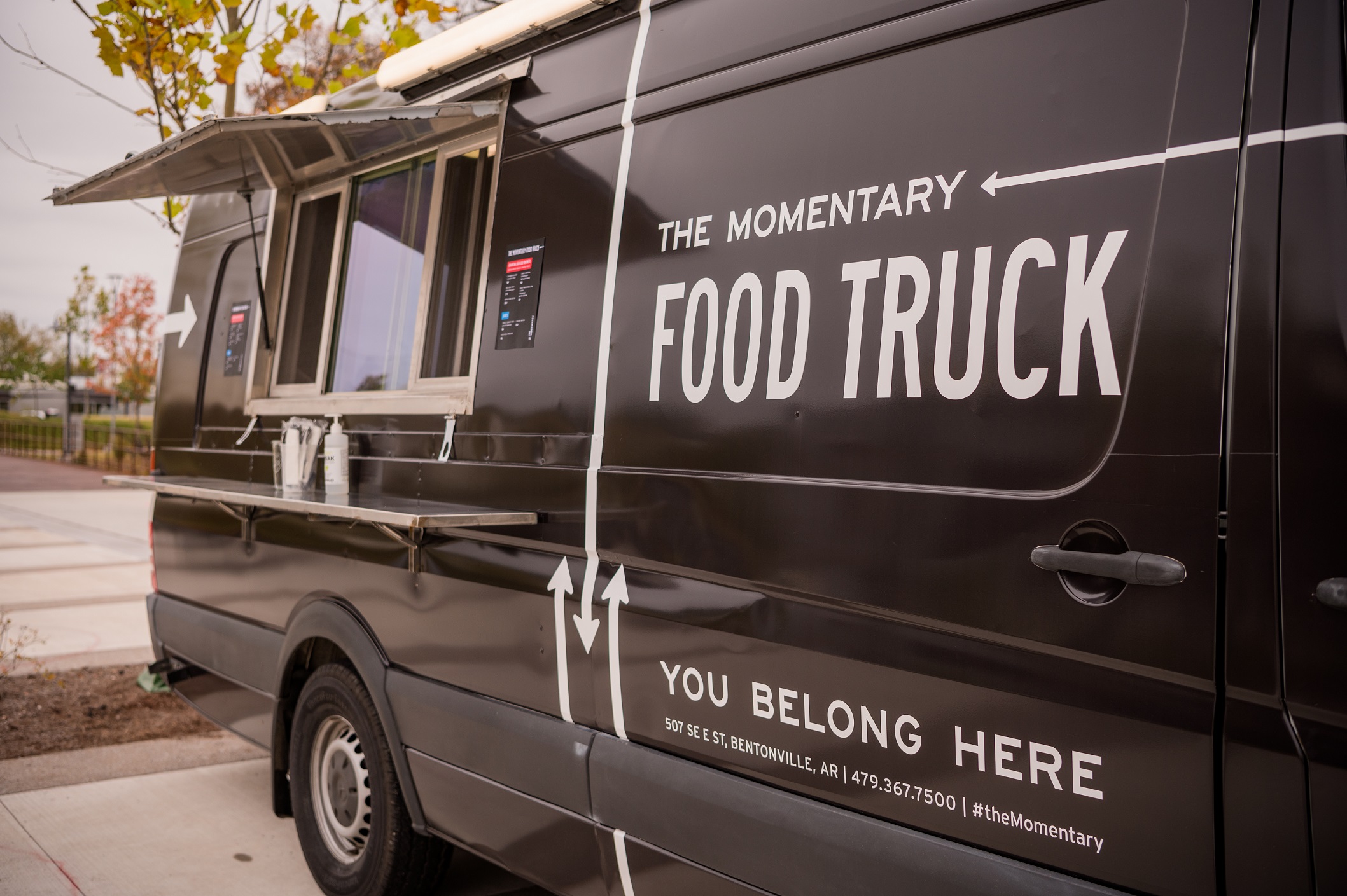 Black truck with white text label and food service window toward the back