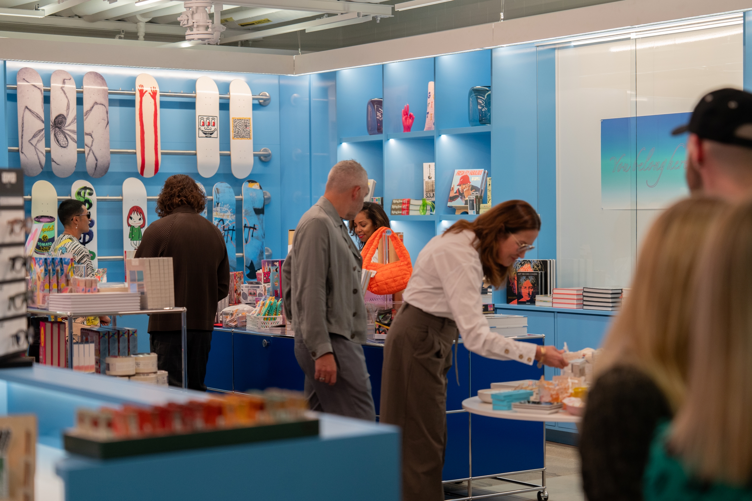 A group of people examine products on shelves in the Momentary shop.