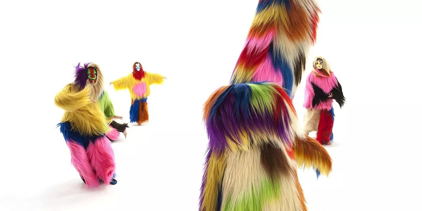 Colorful Soundsuits moving across an endless white background