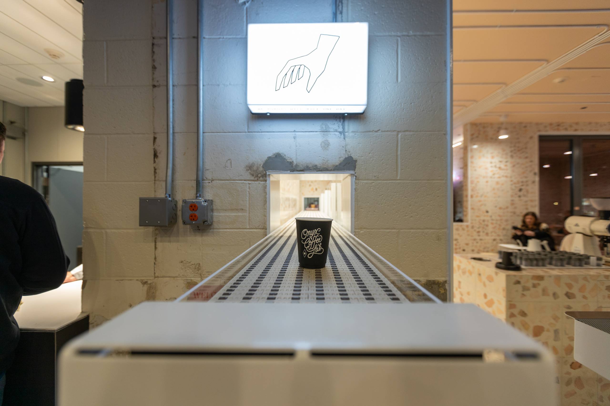 a coffee cup reading onyx coffee lab sits on a conveyor belt