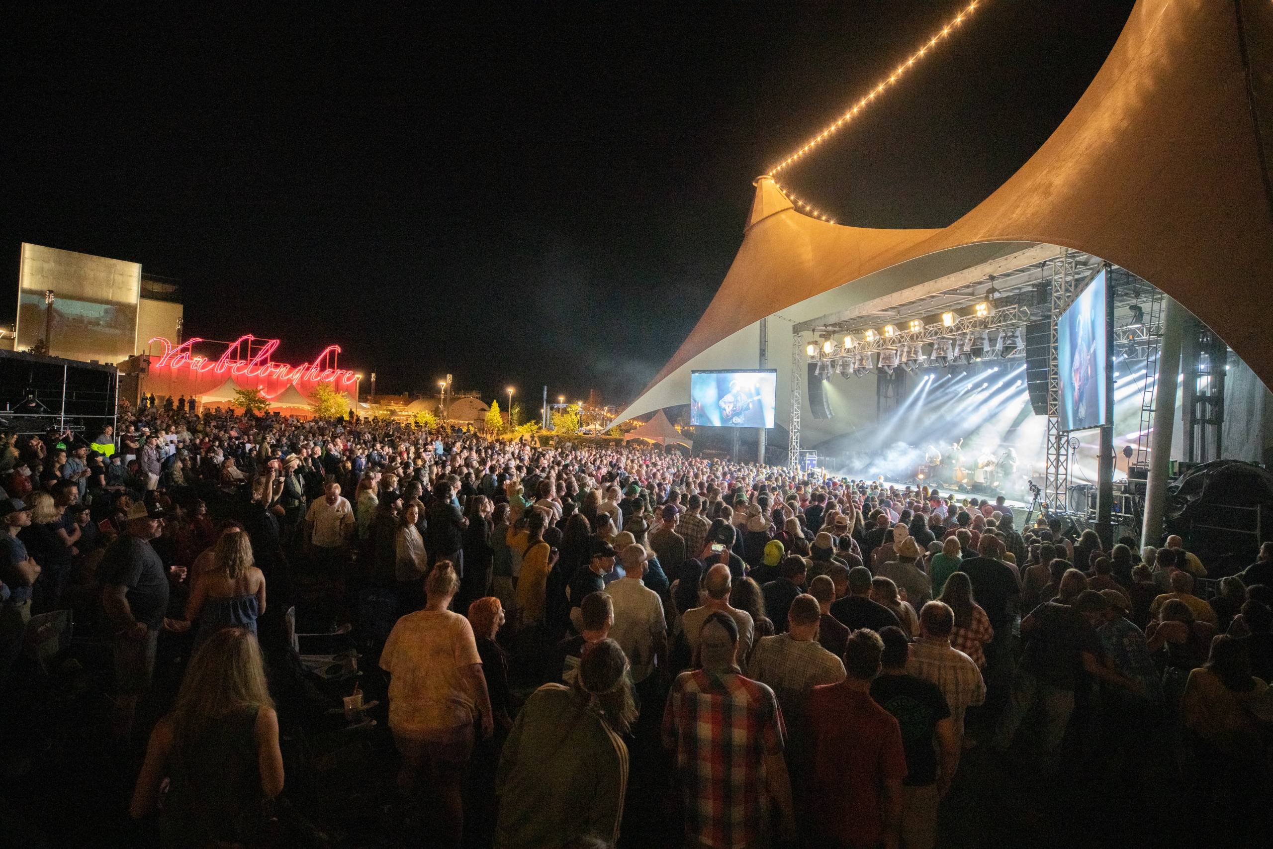 A crowd looks on to the stage on the momentary green at FreshGrass Bentonville 2021 at night