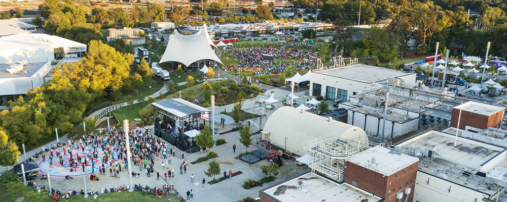 An aerial view of the Momentary and the Momentary Green featuring a canopy tent for performances and people listening to music.