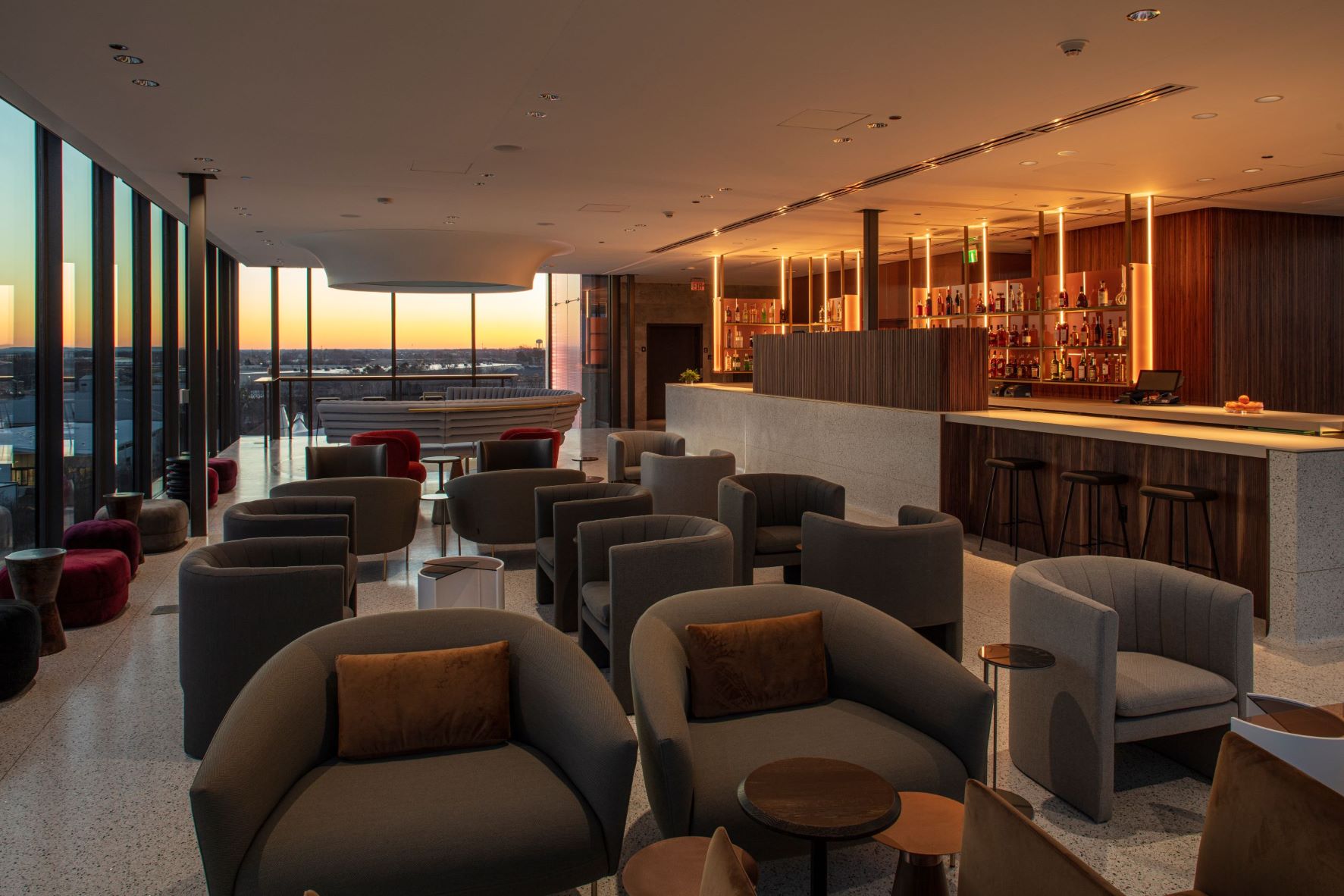 Tower Bar Interior, with a view of a dozen soft chairs, the bar, and large windows showing a view of Bentonville