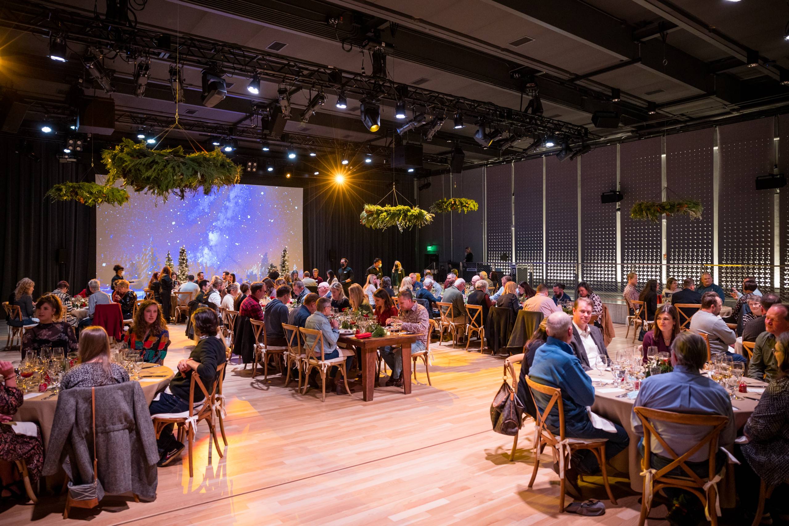 A crowd of people seated in the RØDE House, with holiday decorations and greenery hanging from the ceiling