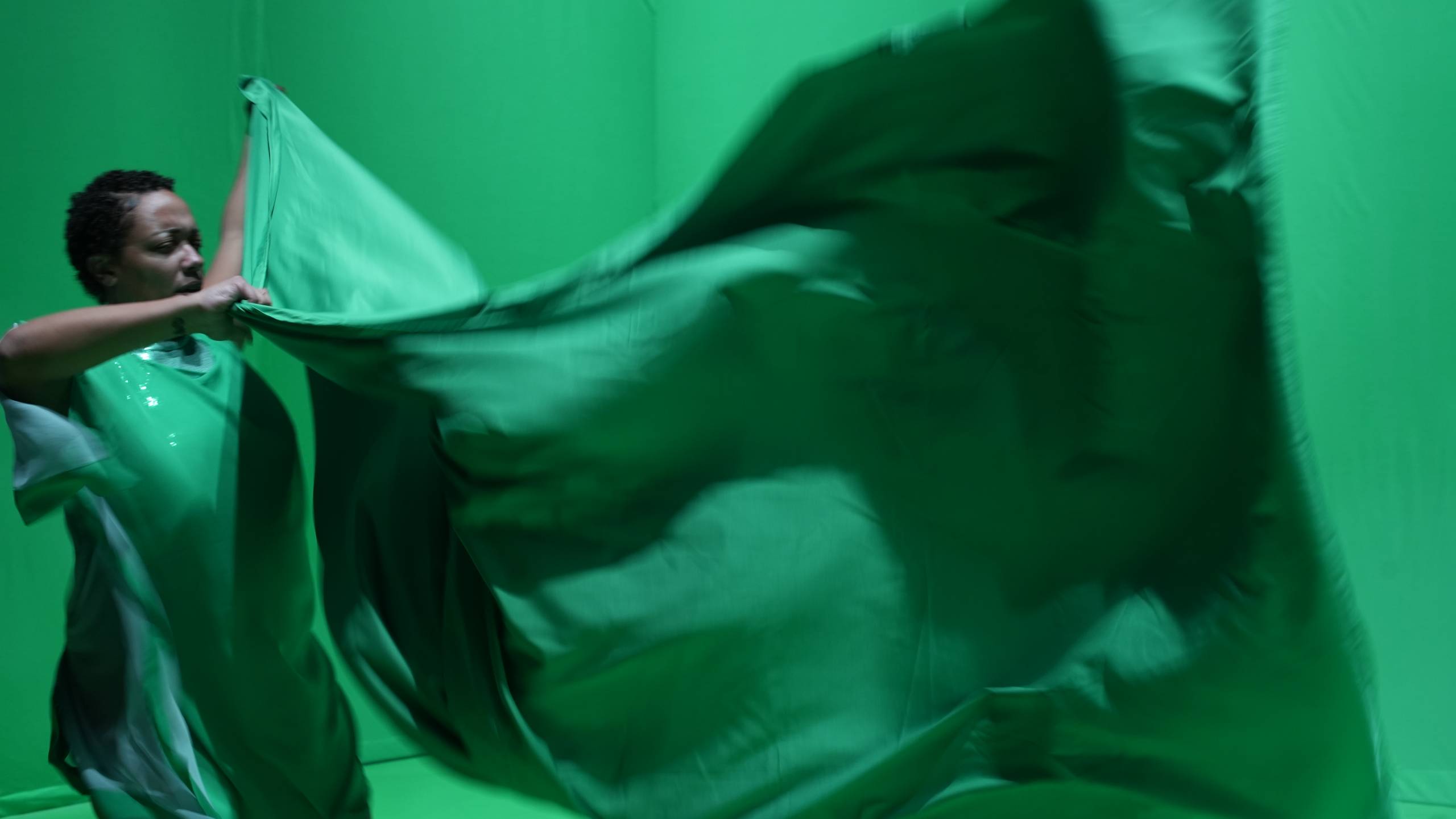 A performer in [siccer] waves green fabric as part of a performance.