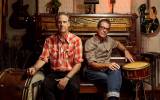 Americana duo Calexico sitting in front of a piano