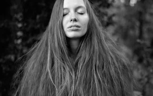 Fotografía en blanco y negro de una mujer con los ojos cerrados y su cabello largo hasta la cintura enmarcando su rostro