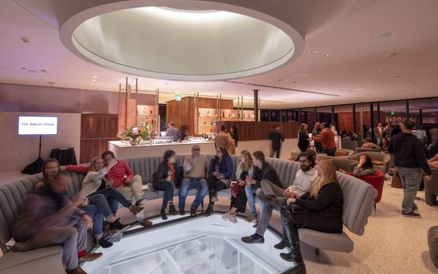 Bar muy concurrido con varias personas sentadas en un sillón circular que rodea un suelo de vidrio transparente