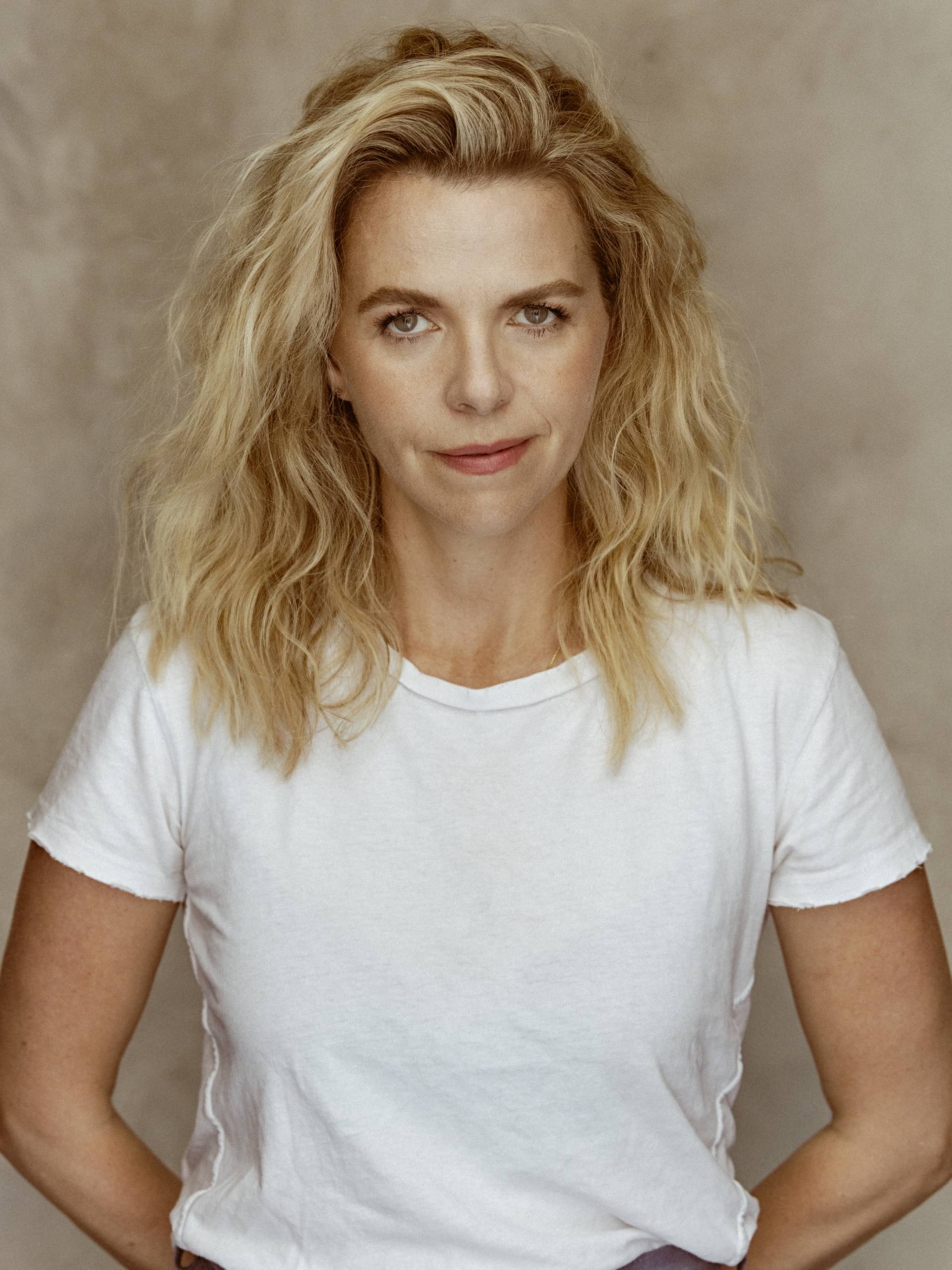 white woman in white shirt standing in front of a beige background