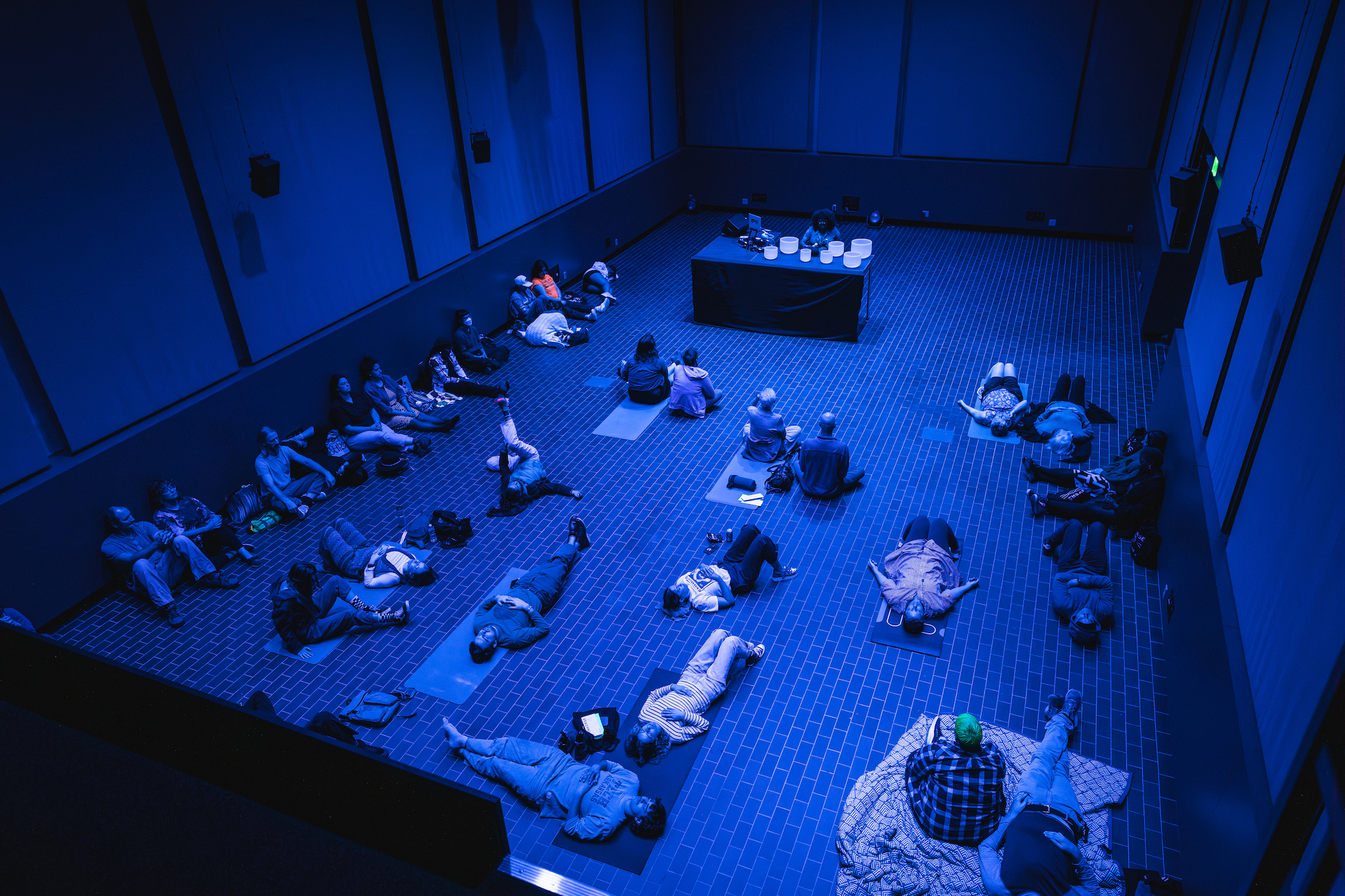 Fermentation Hall People lay and sit on yoga mats in a blue lit room