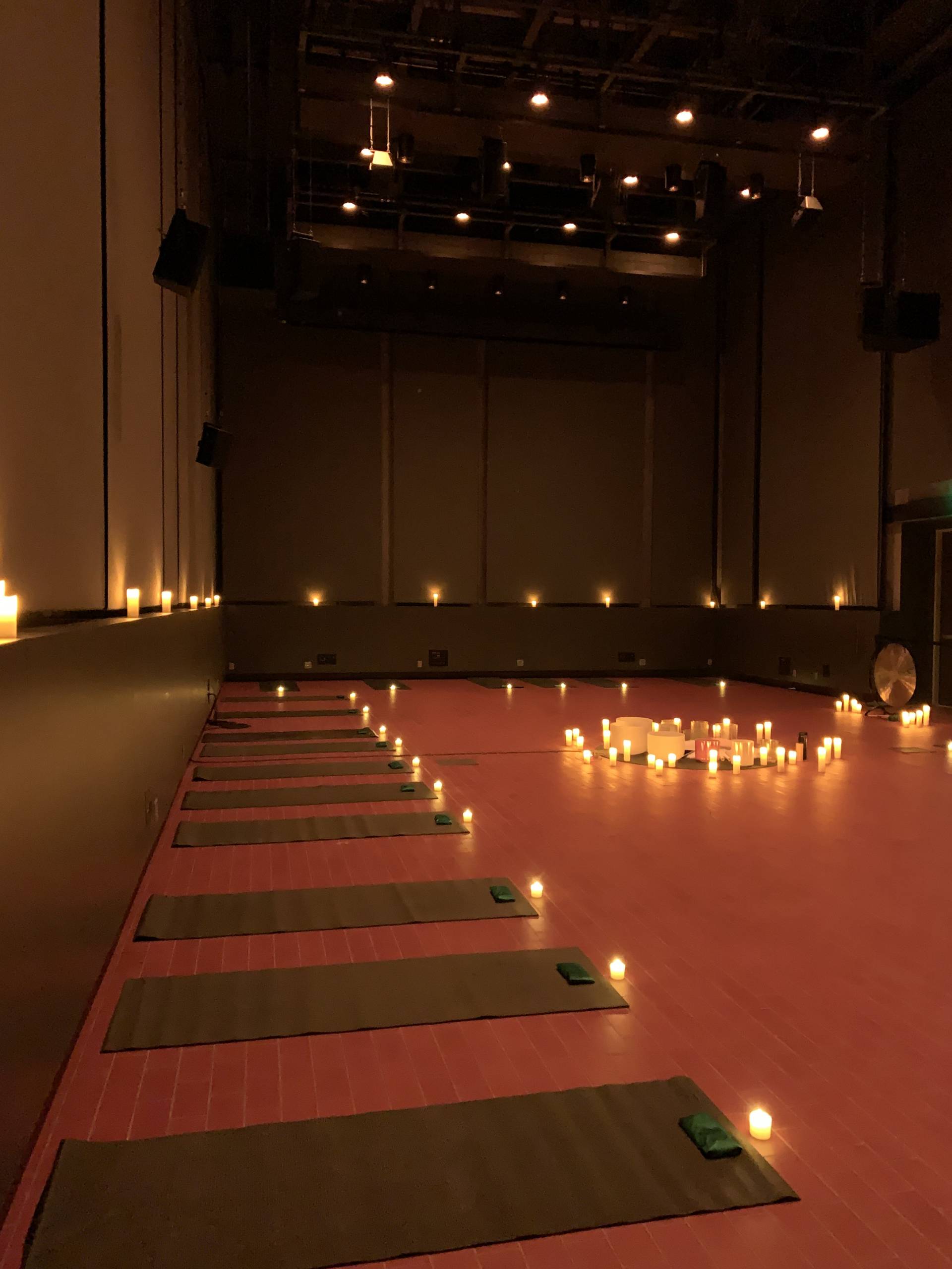 Dimly lit room for yoga with arranged mats and candles creating a serene atmosphere.