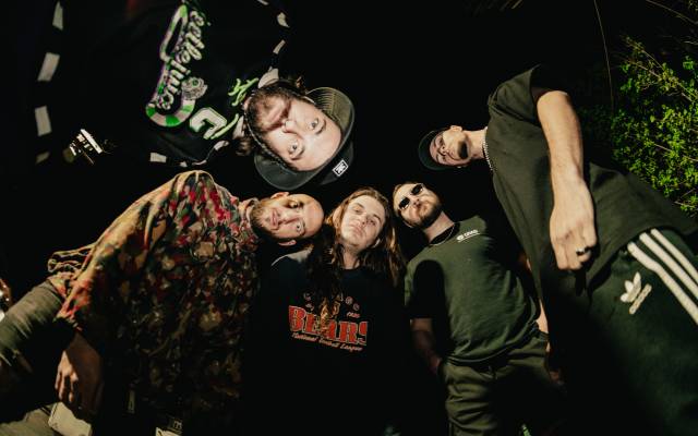 Five individuals in casual attire, shot from below, against a dark background.