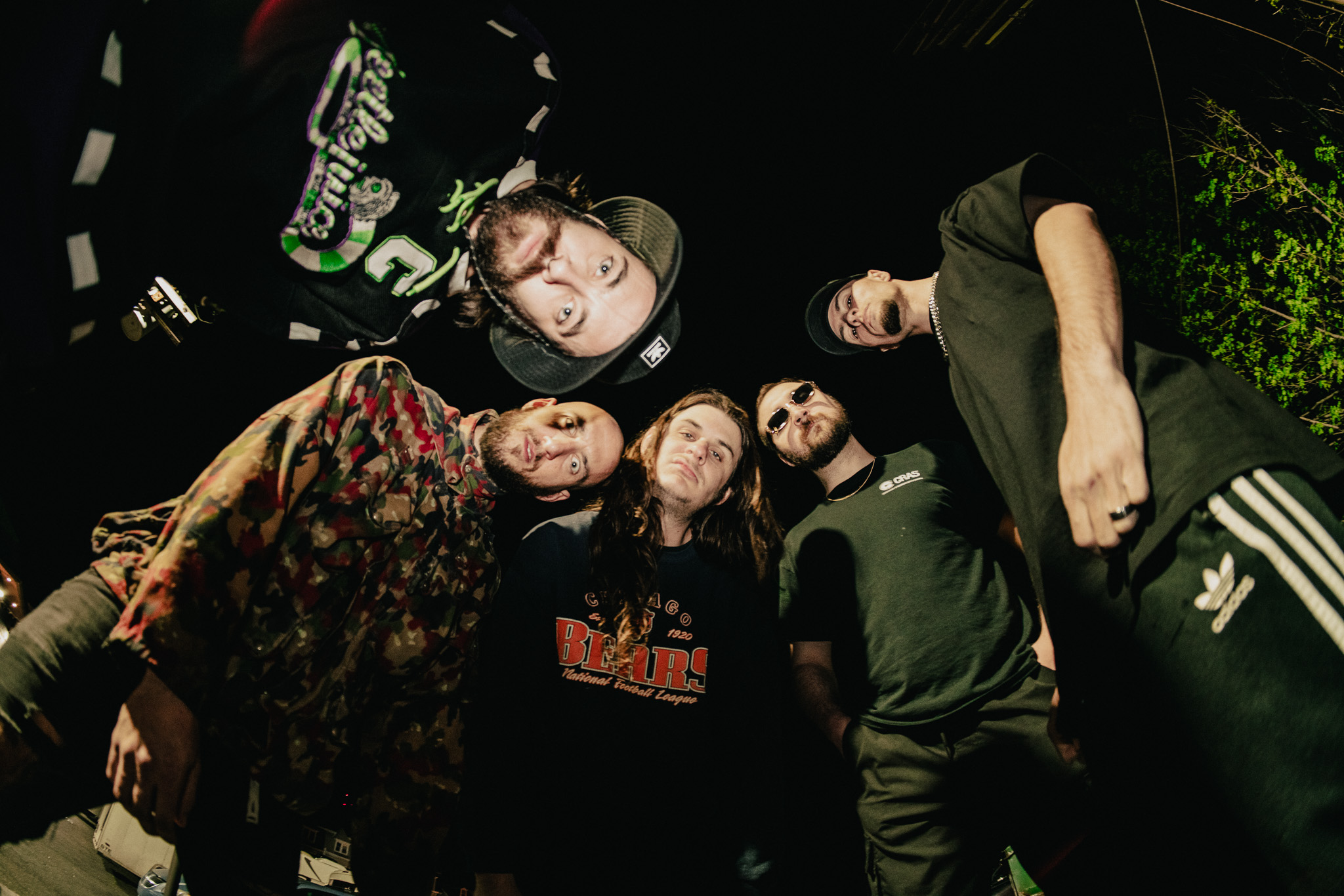 Five individuals in casual attire, shot from below, against a dark background.