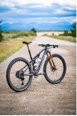 Mountain bike on a gravel road with natural scenery and mountains in the background.