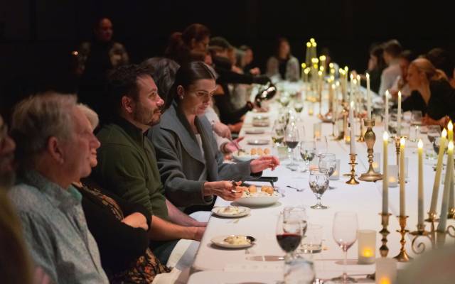 People sitting at a long candle lit table.