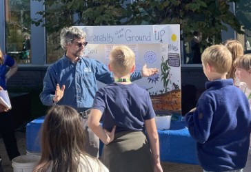 Rob Fanin Person teaching children about soil and sustainability outdoors at educational event.