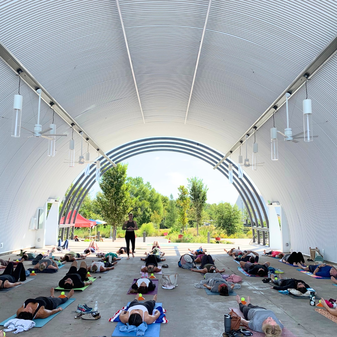 Sunday Reset People in a yoga session under an open arch canopy, surrounded by greenery and natural light.