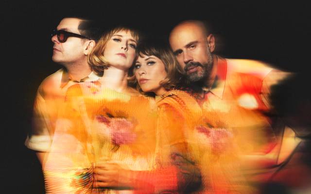 Four people in colorful attire, artistic photo with warm, blurred orange and yellow hues.