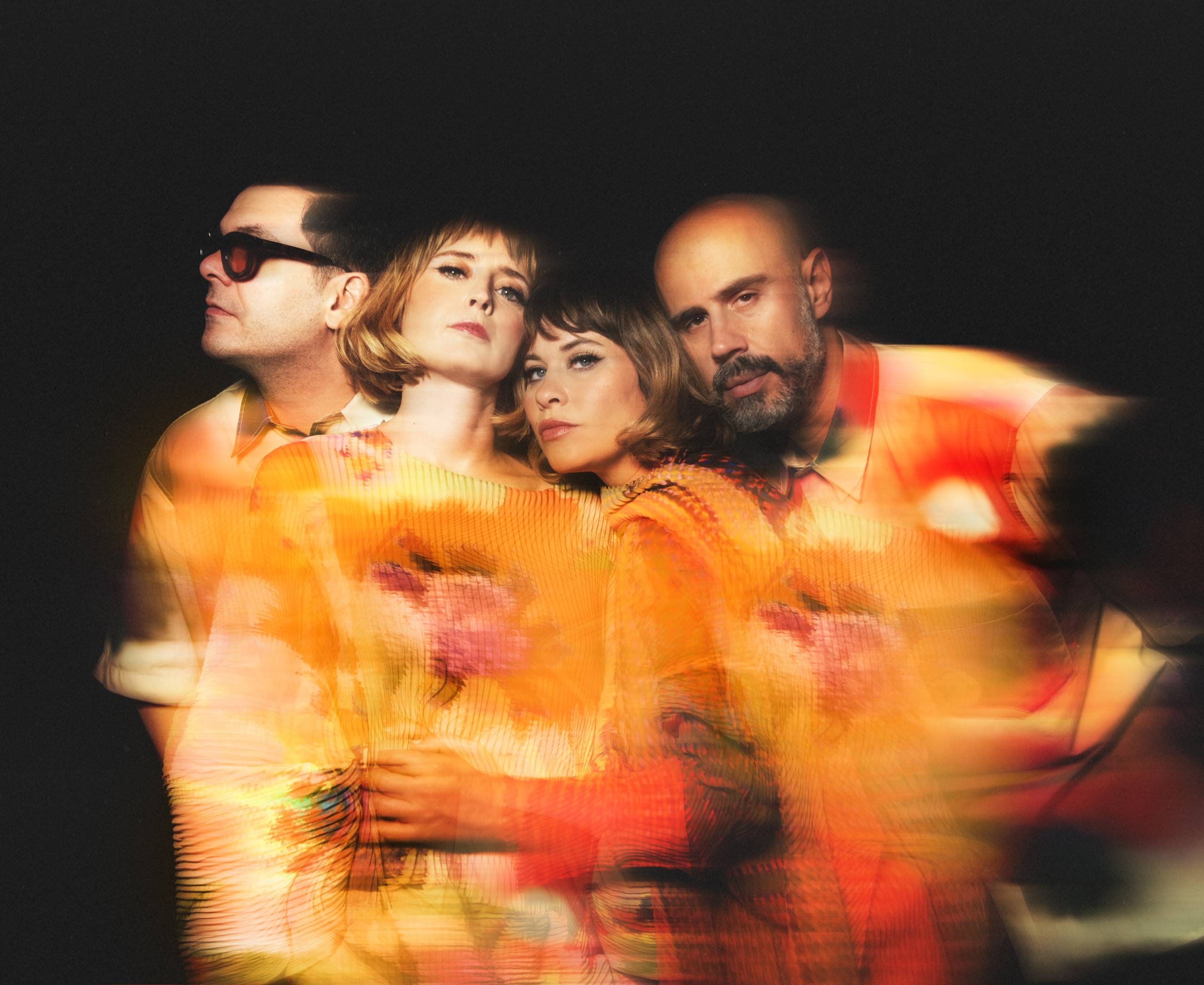 Lucius Four people in colorful attire, artistic photo with warm, blurred orange and yellow hues.