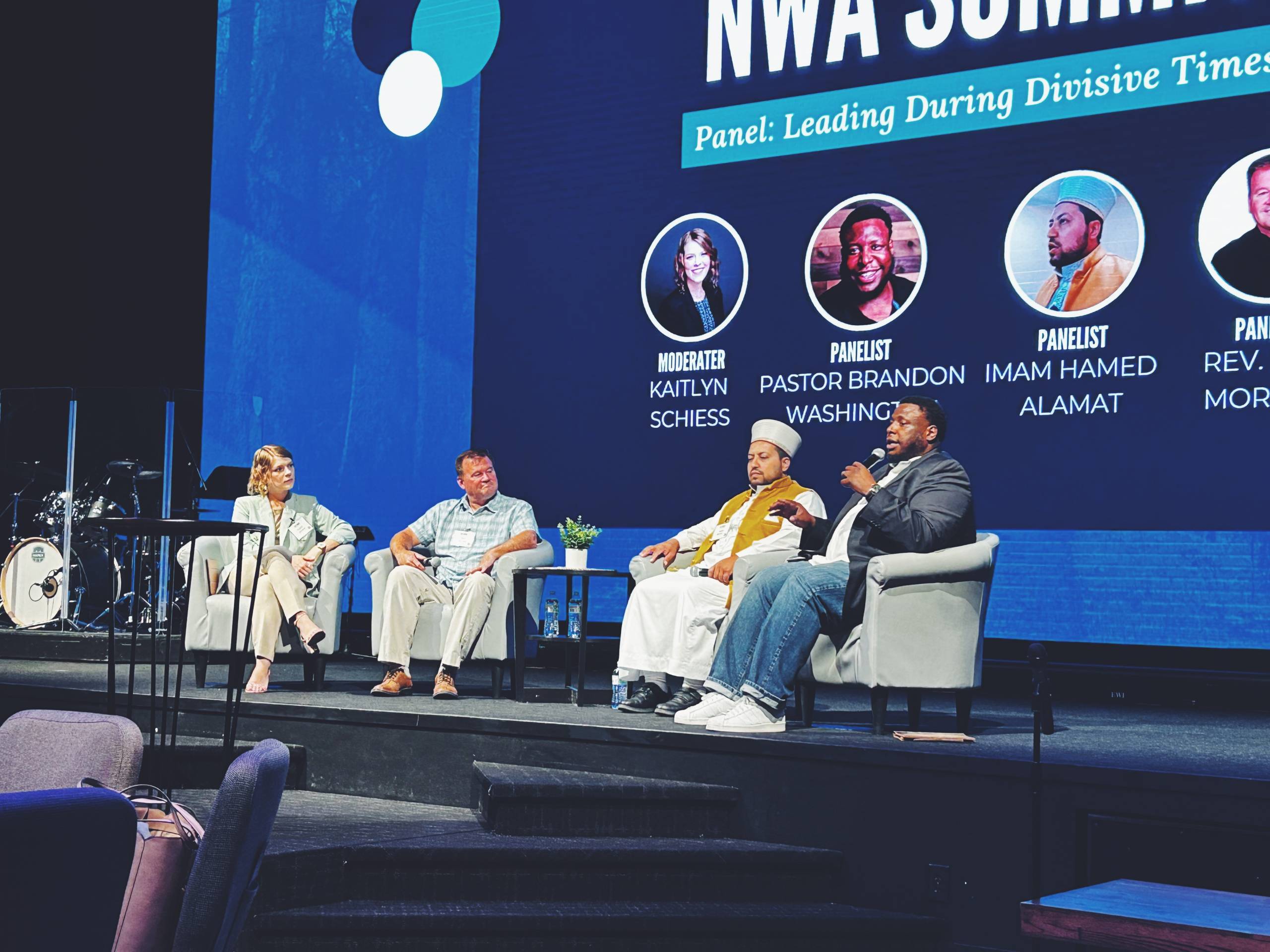 Neighbor to Neighbor Panel discussion on Leading During Divisive Times with four speakers seated on stage.