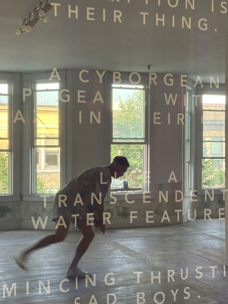 Person bending forward inside a room with large windows and overlaid fragmented text on glass.