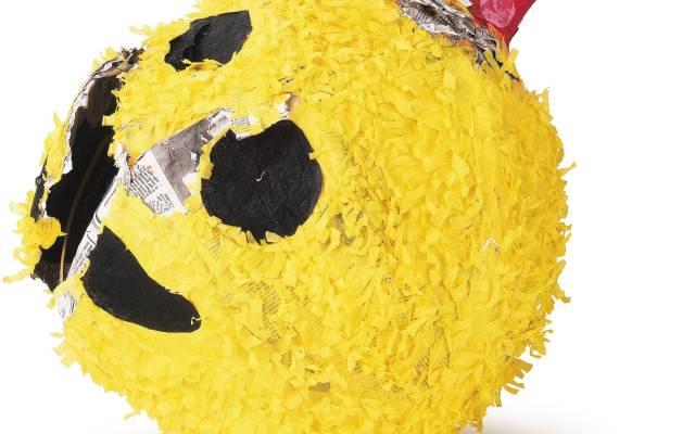 Yellow piñata with a smiling face and a red party hat with colorful polka dots.