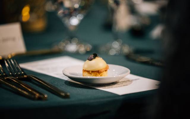 Gourmet appetizer on white plate with silver cutlery and dark green tablecloth background