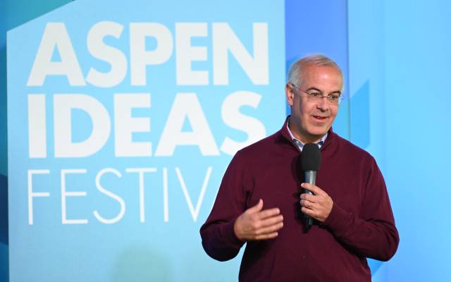 Speaker with microphone on stage at Aspen Ideas Festival, blue backdrop text