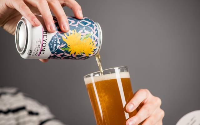 Person pouring beer from a decorated can into a glass.