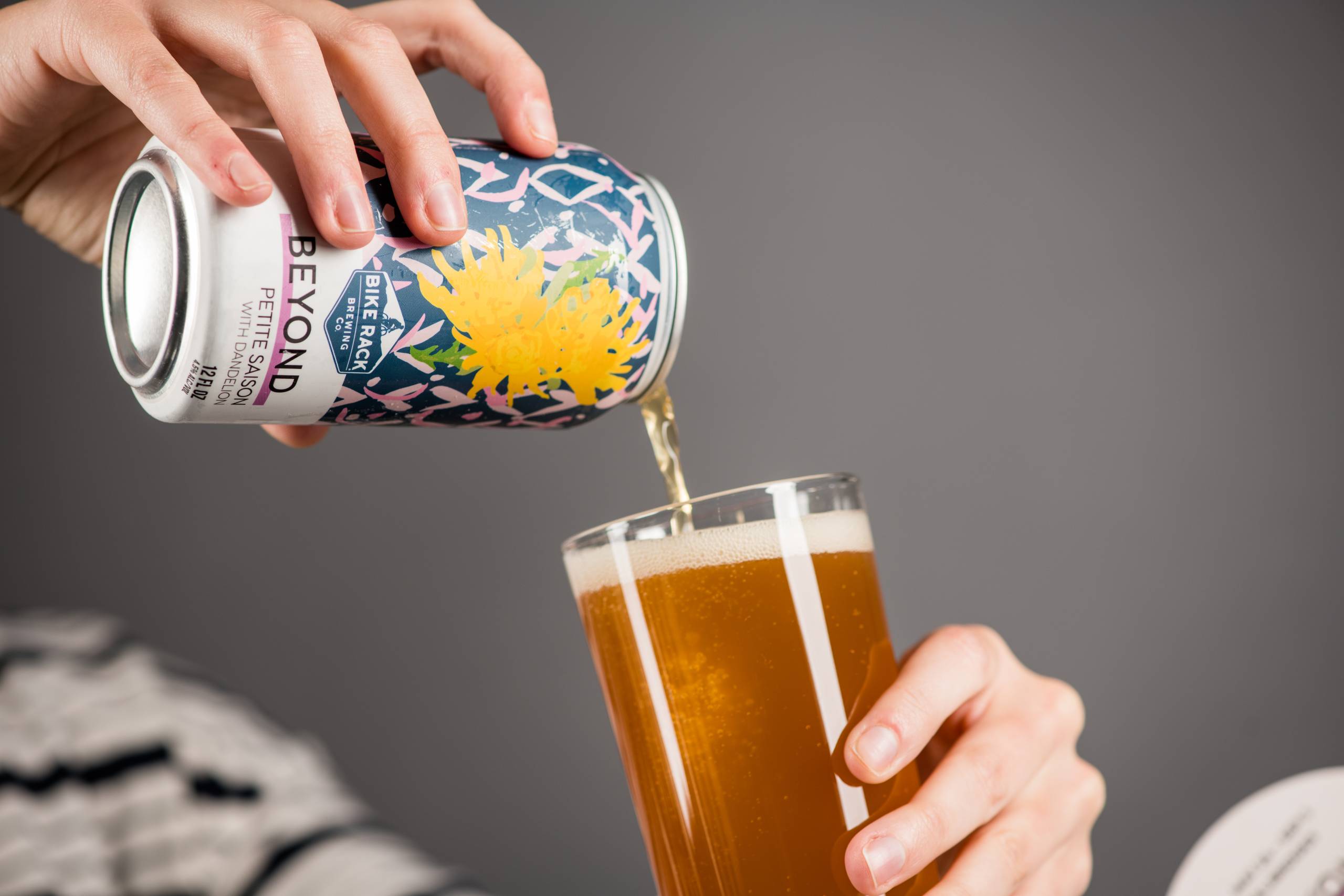 Person pouring beer from a decorated can into a glass.