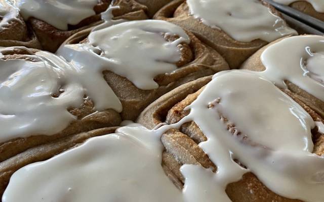 Close-up of toasted cookies with thick white icing drizzled over them on a baking tray.